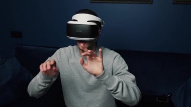 Kafkasyalı bir adamın evde video oyunu oynamak için VR cihazı kullanmasının yavaş çekim videosu.