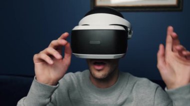 Kafkasyalı bir adamın evde video oyunu oynamak için VR cihazı kullanmasının yavaş çekim videosu.