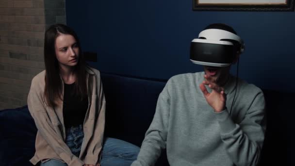 De jonge blanke man gebruikt een virtual reality headset terwijl een aantrekkelijke vrouw naar de man kijkt en glimlacht. Moderne technologie. — Stockvideo