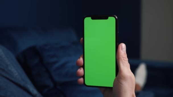 Крупним планом знімок хлопця, який лежить на дивані вночі, тримає смартфон з ключем хроми макет зеленого екрану технологія, з'єднання, концепція зв'язку 4k відео шаблон — стокове відео