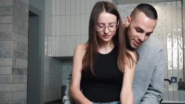 Joven pareja feliz cocinando juntos preparando la cena picando verduras y hablando en casa — Vídeo de stock