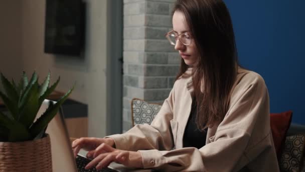 Young caucasian woman using laptop notebook looking at screen typing message, woman chatting on laptop. browsing surfing internet social media studying or working online at home — стоковое видео