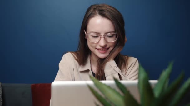 Smiling young caucasian woman using laptop notebook looking at screen typing message, happy lady chatting on laptop. browsing surfing internet social media studying or working online at home — Stok video