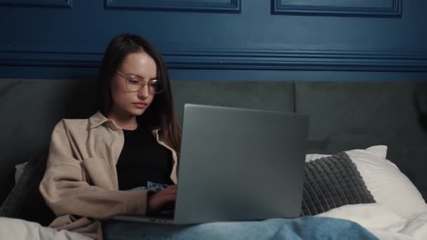 Kobieta pracująca na laptopie w łóżku. dość kaukaskie kobieta pracuje z domu na laptop komputer z sypialni. — Wideo stockowe