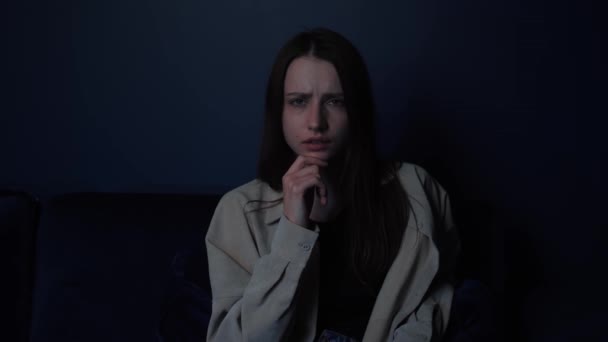 TV 에서 집 소파 기술로 충격을 받고 공포에 떨고 있는 공포 영화를 보고 있는 여성 — 비디오