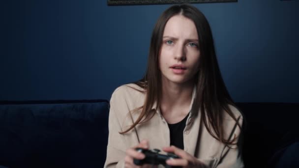 Γυναίκα που παίζει βιντεοπαιχνίδι στο σπίτι τη νύχτα. Ενθουσιασμένη gamer γυναίκα κάθεται σε έναν καναπέ, παίζοντας βιντεοπαιχνίδια σε. — Αρχείο Βίντεο