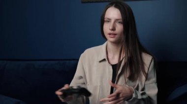 Geceleri evde video oyunu oynayan mutlu bir kadın. Kanepede oturup video oyunlarında oynayan ve kazanan heyecanlı oyuncu kadın..