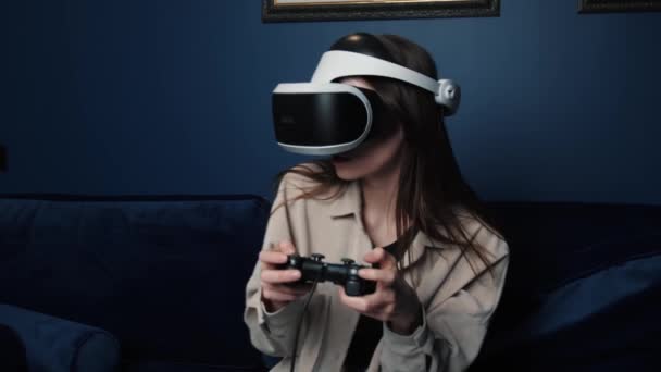 Γυναίκα παίζει video games συναρπαστικό συναίσθημα στον καναπέ στο σπίτι. Χρησιμοποιώντας χειριστήριο joystick και κράνος headset παιχνίδι ελέγχου. Έννοια της εκπαίδευσης, της τεχνολογίας, της ψυχαγωγίας και της εικονικής πραγματικότητας — Αρχείο Βίντεο