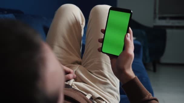 Άνθρωπος ξαπλωμένος στον καναπέ χρησιμοποιώντας έξυπνο τηλέφωνο με chroma κλειδί πράσινη οθόνη τη νύχτα, κύλιση μέσω των κοινωνικών μέσων μαζικής ενημέρωσης ή σε απευθείας σύνδεση κατάστημα - internet, την έννοια της επικοινωνίας κοντά. — Αρχείο Βίντεο