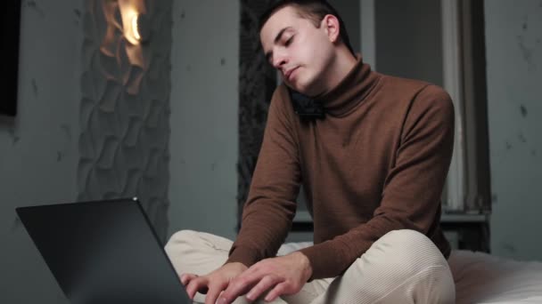 Běloch mluví po telefonu, zatímco doma pracuje s laptopem. Zpomalený pohyb. — Stock video