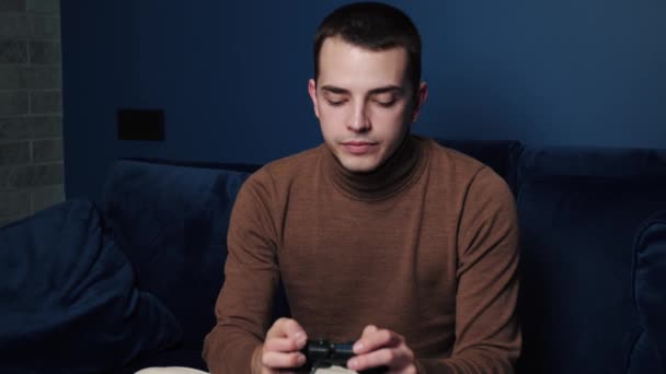 Hombre caucásico cansado sosteniendo controlador, jugando juegos solos en el sofá en casa. Hombre enfocado bostezar jugar juegos, ganar o perder en videojuegos de consola, concepto de hobby. — Vídeos de Stock