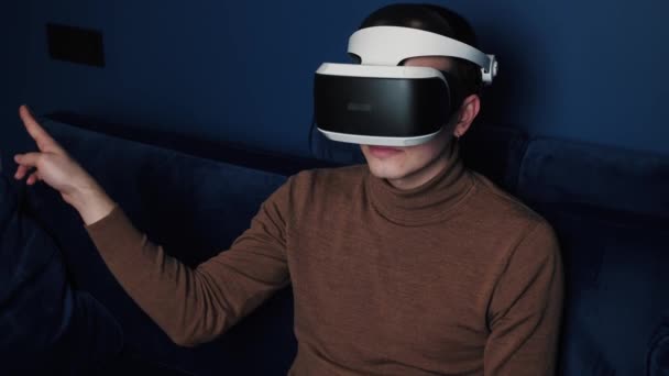 Lassított felvétel egy kaukázusi férfiról, aki egy VR fejhallgató sisakot használ, hogy otthon videojátékokat játsszon. görgetés lehúzása — Stock videók