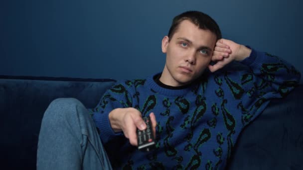 Jeune homme caucasien se détendre sur un canapé confortable, choisir un film en ligne, regarder des programmes divertissants spectacle, passer le week-end libre seul sur le canapé à la maison. — Video