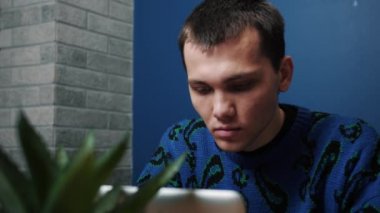 Odaklanmış gülümseyen beyaz adam laptopta çalışıyor ve daktilo yazıyor. Bilgisayarı kullanan genç profesyonel bir erkek ofis masasında oturuyor..
