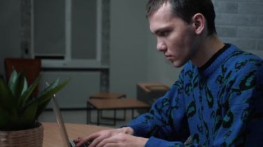 Kafkasyalı bir adam laptopta çalışıyor ve daktilo kullanıyor. Bilgisayarı kullanan genç profesyonel bir erkek ofis masasında oturuyor..