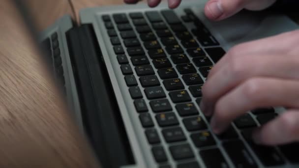 Közelkép férfi kezét gépelés laptop billentyűzeten ül az asztalnál otthon vagy az irodában — Stock videók