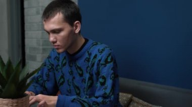 Evde ya da ofiste çalışan ve bilgisayarını kullanan odaklanmış genç bir adam..