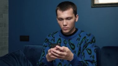 Heyecanlı beyaz erkek öğrenci elinde akıllı telefon tutuyor. İnternetteki telefondan şaşkına dönüyor. Telefona bakan mutlu adam iyi haberleri okuyor.