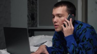 Yatak odasında cep telefonuyla konuşan yakışıklı, beyaz bir adam. Portre adam yatakta dinleniyor ve akıllı telefonda sohbet ediyor.