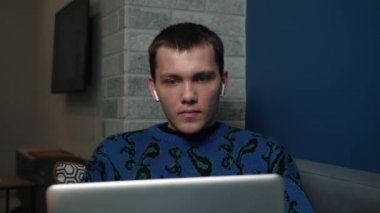 Kulaklık takan, evde ya da iş yerinde laptopunu kullanan heyecanlı bir genç adam. Haberler iyi, mutlu adam..