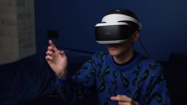 Kafkasyalı bir adamın evde video oyunu oynamak için kulaklık kullandığı yavaş çekim videosu. kaydırma kaydırma