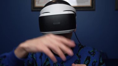 Kafkasyalı bir adamın evde video oyunu oynamak için kulaklık kullandığı ağır çekim videosunu kapat. kaydırma kaydırma