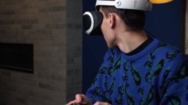Çekici heyecanlı beyaz adam joystick 'i tutuyor ve evdeki koltukta sanal gerçeklik gözlüğü başlığı takıyor. Evde VR gözlük kullanarak oyun oynayan mutluluk oyuncusuName.
