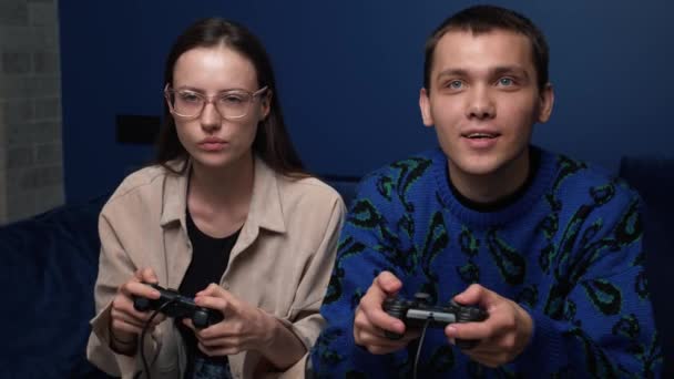 Glückliche junge Leute, die Videospiele auf der Konsole spielen, während sie auf der Couch vor dem Fernseher sitzen. Millennial-Paar verbringt lustige Zeit zu Hause. — Stockvideo