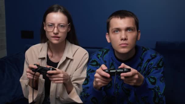 Jovens felizes jogando videogames no console enquanto se sentam no sofá na frente da TV. Millennial casal passar tempo divertido juntos em casa. — Vídeo de Stock