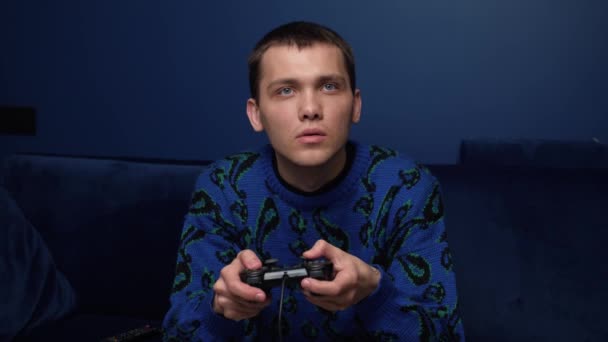 Front view of an excited caucasian man playing video games and using joystick controller. Tired man playing games on sofa at home. — Stock Video