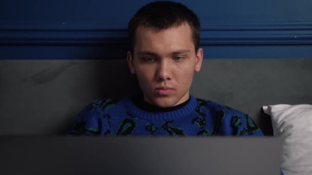 Młody, przystojny biały mężczyzna pracujący na laptopie leżącym w łóżku w domu. Man surfing internet lub rozmowy z przyjaciółmi online na laptopie relaks w łóżku w domu. — Wideo stockowe