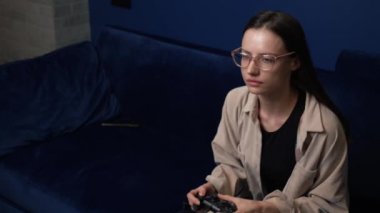 TV karşısında kanepede otururken konsolda video oyunu oynayan mutlu gençler. Milenyum çifti evde birlikte eğleniyor..