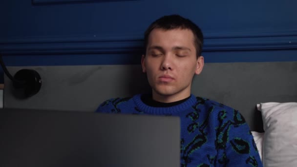 Giovane caucasico stanco che lavora e digita sul computer portatile sul letto a tarda notte, poi sbadiglia addormentandosi. — Video Stock