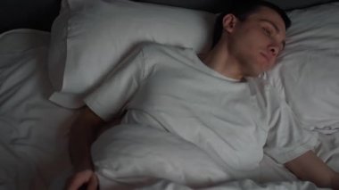 Sakin yakışıklı adam rahat rahat bir yatakta uyur. Sağlıklı ve güzel bir uyku uykusunun tadını çıkarır..