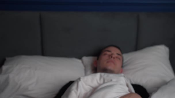 Vista frontal del joven caucásico sorprendido durmiendo y levantándose rápido mientras está acostado en la cama. — Vídeo de stock
