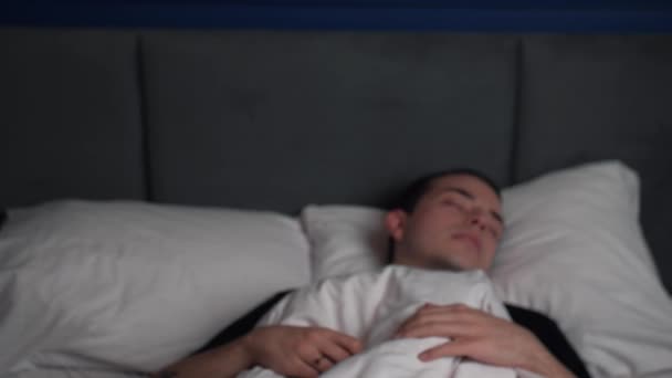 Elöl a döbbent fiatal kaukázusi férfi elalszik, és gyorsan felkelni, miközben fekszik az ágyban. — Stock videók
