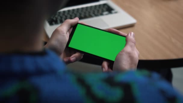 Fecho de um telefone com uma tela verde. Chroma chave na tela do smartphone. Um homem segurando tela verde do telefone e assistindo vídeo. Cliques e furto. — Vídeo de Stock