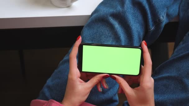 Cierra las manos de mujer sosteniendo el teléfono inteligente de pantalla verde cromakey viendo contenido o video en casa. Gadgets concepto de personas. — Vídeo de stock