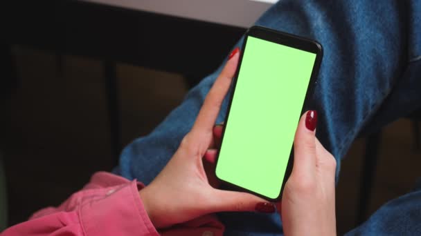 Крупним планом жінка тримає хроматичний зелений екран смартфона, дивлячись контент або відео вдома. Гаджети концепція людей . — стокове відео