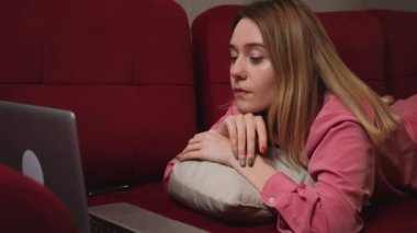 Evdeki kanepede yatan dizüstü bilgisayara bakarak yorgun üzgün kadın yüzünü kapat. İşindeki hataları düşünen üzgün bir kadına yaklaş. Laptop görünümlü üzgün kız portresi. Bunalımlı çalışan