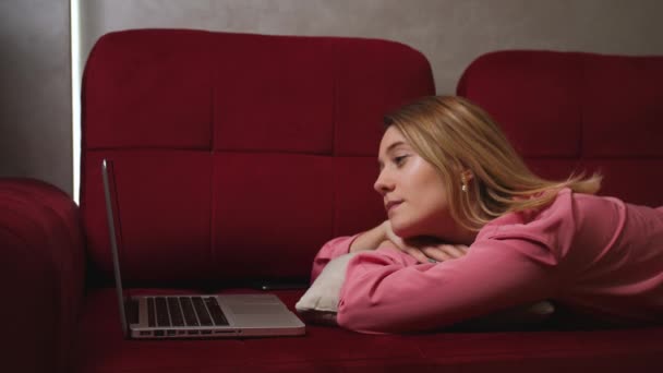 편안 한 여성이 노트북 화면을 보고, 즐거운 이메일 뉴스를 읽고, 내용을 보고, 소파에서 혼자 편안 함을 느끼고, 집에서. — 비디오