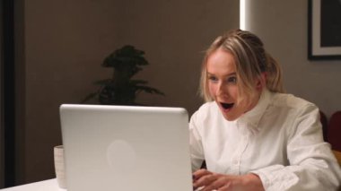 Heyecanlı genç bayan kazanan dizüstü bilgisayara bakıyor online başarıyı kutluyor evde oturuyor. Kadın yeni iş fırsatları elde eder, e-postada iyi haberler okur, zafere sevinir, motive olur..