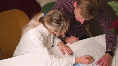 Genç adam ve kadın evde ders çalışıyor, öğrenciler notlar alıyor, erkek ve kadın öğretmenler evde defterlerle ders veriyor.. 