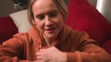 Gülümseyen çekici genç bir kadın koltukta dinleniyor. Derin bir nefes alıyor. Ellerini başının arkasında tutuyor..