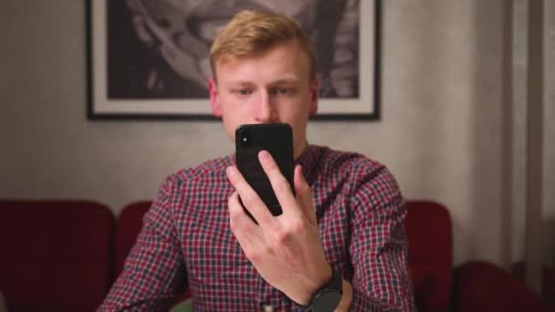 Hombre guapo caucásico mostrando teléfono móvil con cromakey pantalla verde sentado en el sofá en casa, — Vídeo de stock