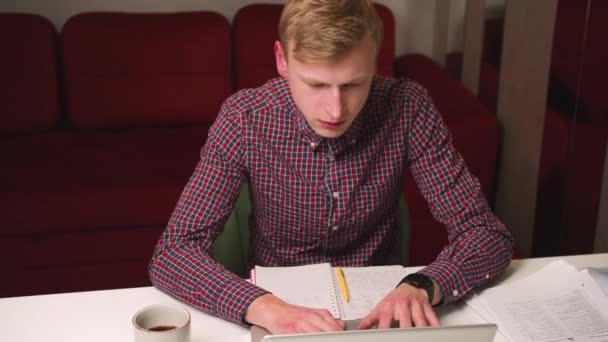Zmęczony młody biały mężczyzna pracuje i pisze na laptopie w biurze w domu późno w nocy, mężczyzna używa laptopa i ziewanie. — Wideo stockowe
