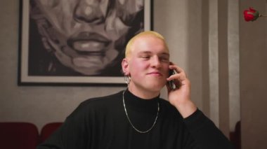 Sarı saçlı, manikürlü, telefonda konuşan ve evde kahve içen yakışıklı, mutlu homoseksüel adam..