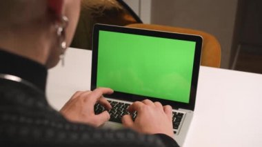 Arkadan bak. Homoseksüel erkek ellerini dizüstü bilgisayara, evde çalışan yeşil ekran kromatonuna yaz. Klavye yazan eller, internet, yeşil ekran, kromaanahtar, sosyal ağ arayışı. Buradan çalış