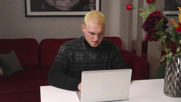 Förvånad homosexuell man skriva på laptop gör forskning, online kommunikation. Chockad ung man med bärbar dator, har goda nyheter, sitter hemma kontor skrivbord. — Stockvideo