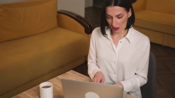 自宅やオフィスでノートパソコンで働く美しい実業家。家のオフィスでラップトップで働いている間に女性があくびをする. — ストック動画